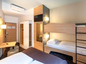 a bedroom with two bunk beds and a desk at B&B Hotel Hildesheim in Hildesheim
