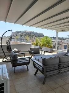 a patio with couches and chairs on a roof at V&V Acropolis view apartment in Athens