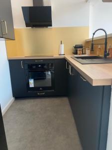 a kitchen with a black oven and a sink at Le Foyer d'Or - Hypercentre & Confort in Agen