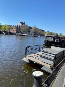 a boat tied to a dock on a river at Houseboat Amstel River Studio in Amsterdam