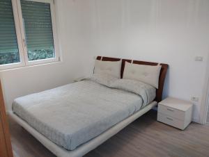 Cama en habitación blanca con 2 ventanas en Alloggio Via Bertini, en Firenzuola