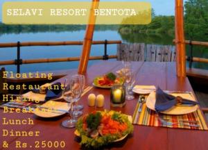 Selavi Resort Bentota في بينتوتا: طاولة مع الطعام وكؤوس النبيذ على متن قارب