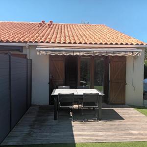 una mesa y sillas en una terraza con una casa en Maison avec piscine commune à 800m de la plage, en Brem-sur-Mer