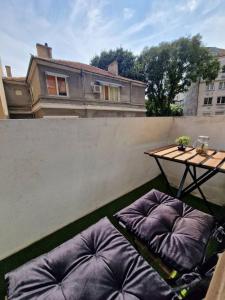 Central Luxe Apartment - Elisha في مدينة فارنا: شرفة مع الوسائد الأرجوانية وطاولة على سياج