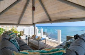 a living room with a couch and a view of the ocean at Ocean Pebbles, The Sound of the Sea in Punta de Mujeres