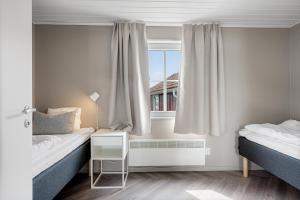 a bedroom with two beds and a window at Tanumstrand SPA & Resort Stugor in Grebbestad