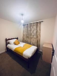 a bedroom with a bed with a yellow blanket and a window at Stunning 3 bed home at the heart of Wolverhampton in Wolverhampton