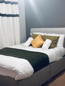a bed with green and white sheets and pillows at Stunning 3 bed home at the heart of Wolverhampton in Wolverhampton