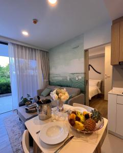 2 br Laguna, SkyPark, Bang Tao في تالانغ: غرفة معيشة مع طاولة مع وعاء من الفواكه عليها