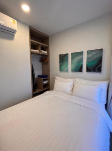 a bedroom with a white bed with three paintings on the wall at 2 br Laguna, SkyPark, Bang Tao in Thalang