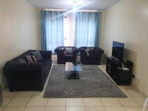 a living room with two couches and a tv at Spacious 3bedroom in Greatwall Gardens in Athi River