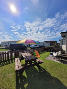 a picnic table with an umbrella in a yard at 72 Holiday Resort Unity Brean Centrally Located - Resort Passes Included - Pet Stays Free No workers Sorry in Brean