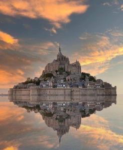 a castle on an island in the water at sunset at Le Chalet de St Vigor in Saint-Vigor-le-Grand