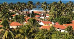un gruppo di case con palme e l'oceano di Casa Yuka Guajiru a Trairi