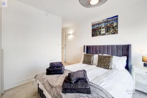una camera da letto con un grande letto con asciugamani viola di Luxury New 2 Bed/2 Bathroom Flat With Balcony a Edgware