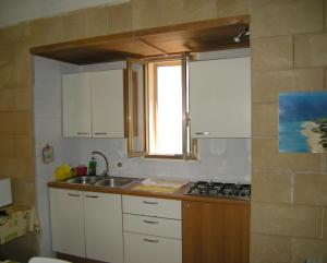 レウカにあるLa Dimora Del Pescatoreの白いキャビネット、シンク、窓付きのキッチン