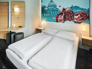 a bedroom with a bed and a picture of a motorcycle on the wall at B&B Hotel Bad Homburg in Bad Homburg vor der Höhe