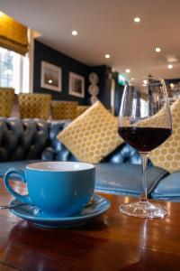 a glass of wine and a cup on a table at Rose & Crown Rooms in Beverley