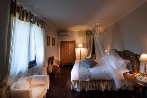 a bedroom with a bed and a chair and window at Agriturismo Tra Le Vigne in Buttrio