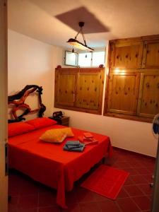 1 dormitorio con cama roja y armarios de madera en Casa belvedere Sa Costa, en Dorgali