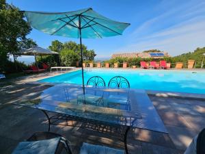 a table with an umbrella next to a swimming pool at Villa delle lucciole in Massa Martana