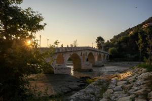 uma ponte de pedra sobre um rio com o pôr do sol em Hotel Kapllani em Berat