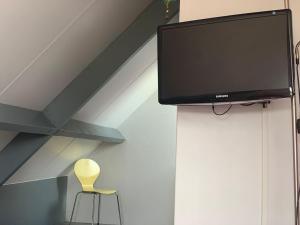 a chair and a flat screen tv on a wall at Mooie schuur appartement in Den Horn 