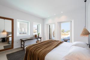 a bedroom with a bed and a desk and windows at Exclusive Luxury Moca beachfront villa, Molos, Paros in Molos Parou
