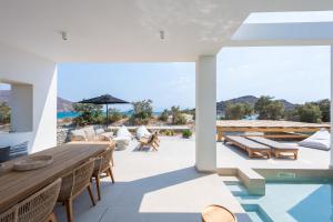 an outdoor patio with a wooden table and chairs at Exclusive Luxury Moca beachfront villa, Molos, Paros in Molos Parou