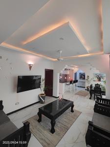 uma sala de estar com uma mesa e uma televisão na parede em Ayaa Luxury Apartment 4th Floor Zanzibar em Zanzibar