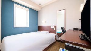 a bedroom with a bed and a desk with a computer at Super Hotel Naha Shintoshin in Naha