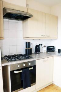 a kitchen with a stove and white cabinets at 2 bed flat near Milton Keynes city centre in Milton Keynes