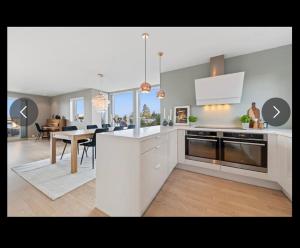 a kitchen with white cabinets and a dining room with a table at Moderne funkis med fantastisk havutsikt in Asker