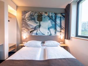 a bedroom with a bed with a picture on the wall at B&B Hotel München-Olympiapark in Munich