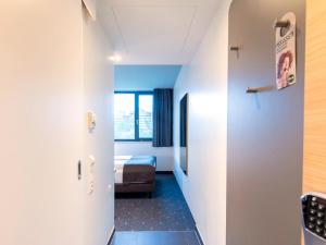 un couloir menant à une chambre avec un lit dans l'établissement B&B Hotel München-Olympiapark, à Munich