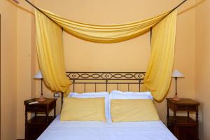 een slaapkamer met een bed met gele gordijnen erboven bij Gattamelata, Historic Flat with Modern Comforts in Migliano