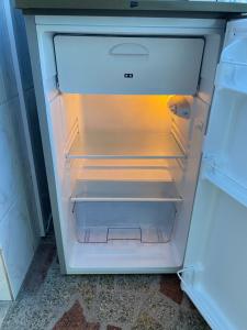um frigorífico vazio com a porta aberta numa cozinha em Garsoniera 27mp - Camera - Baie - Bucatarie - Balcon em Mogoşoaia