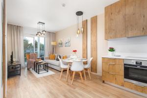 a kitchen and living room with a table and chairs at Perłowa Przystań Seaside Apartment by Noclegi Renters in Sianozety