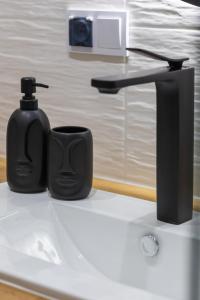 a black soap dispenser sitting on top of a sink at Perłowa Przystań Seaside Apartment by Renters in Sianozety
