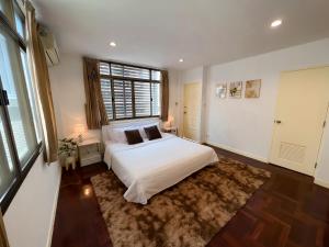 um quarto com uma cama branca e uma grande janela em Sukhumvit 31 Sweet Home 7 beds - up to 12 guests em Bang Kapi