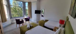 a hotel room with two beds and a table at The Pitlochry Hydro Hotel in Pitlochry