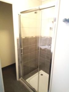 a glass shower in a bathroom with a sink at Hôtel Restaurant Bar du Commerce - KB HOTEL GROUP in Tronget