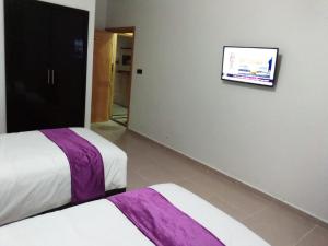 um quarto com duas camas e uma televisão na parede em HOTEL NASSIM AL-BAHR em Dakhla