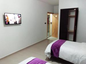 um quarto com uma cama e uma televisão na parede em HOTEL NASSIM AL-BAHR em Dakhla