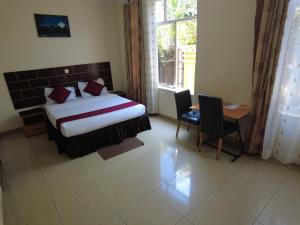 um quarto com uma cama, uma secretária e uma janela em DANA KIGALI HOTEL em Kigali