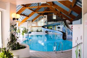 a large swimming pool with a slide in a building at Hotel Stockhausen in Schmallenberg