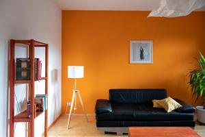- un canapé noir dans le salon avec un mur orange dans l'établissement Karl die Große Ferienwohnung, à Dessau