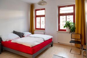 a bedroom with a red and white bed with windows at Karl die Große Ferienwohnung in Dessau