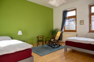 zieloną sypialnię z 2 łóżkami i krzesłem w obiekcie Karl die Große Ferienwohnung w mieście Dessau