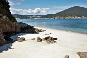 una playa con rocas, agua y montañas en Cabañita en Playa Caolin, en O Vicedo